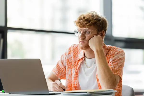 A man focused on his laptop at a table in a library. — Stock Photo