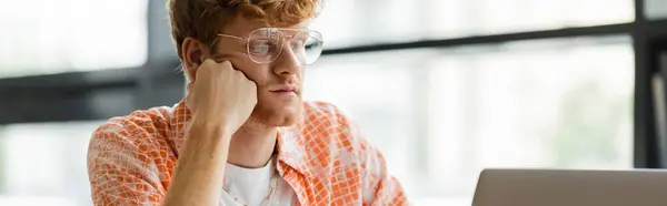 A man with glasses sits in front of a laptop. — Stock Photo