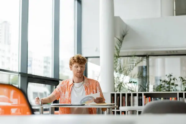 A man engrossed in a book at a table. — Stock Photo