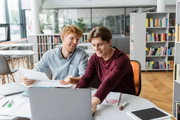 Zwei junge männliche Studenten arbeiten zusammen an einem Tisch mit einem Laptop. — Stockfoto