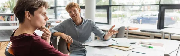 Due giovani studenti maschi in pieno studio a un tavolo della biblioteca. — Foto stock