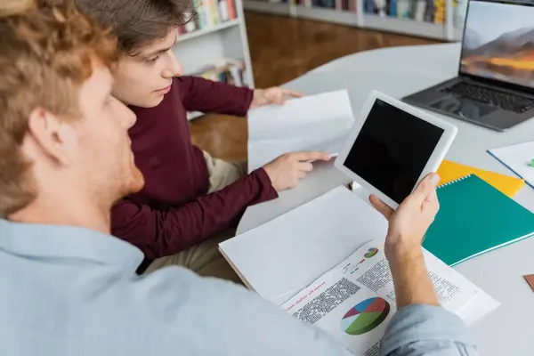 Two students engaged in focused study on a laptop at a table in a library. — Stock Photo