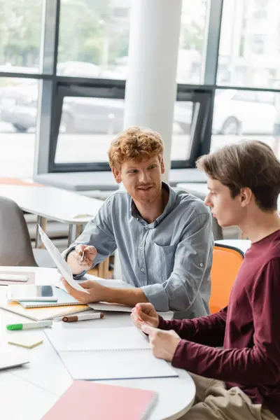 Young male students engaged in focused studying at a library table. — Stock Photo