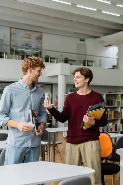 Two young men engrossed in conversation at a library. — Stock Photo