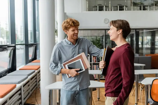 A man engages in a lively discussion with his friend in a book-filled library. — Stock Photo