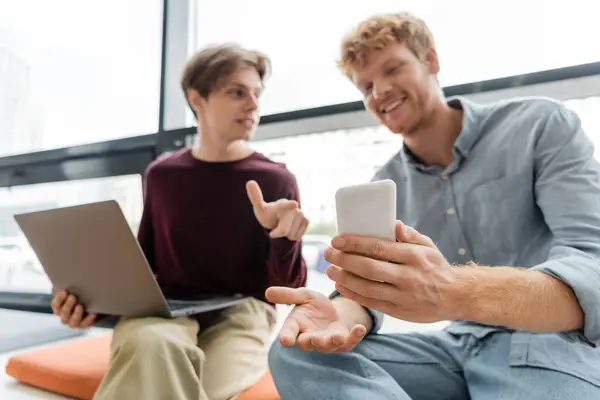 Two male students engrossed in a cell phone while sitting on a couch. — Stock Photo