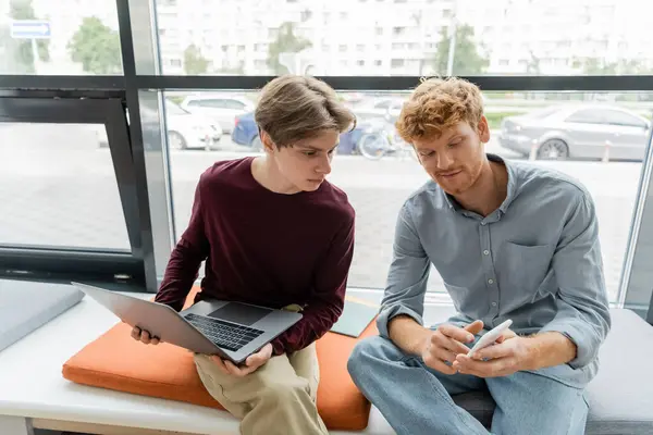 Two students on bench, focused on laptop screen. — Stock Photo
