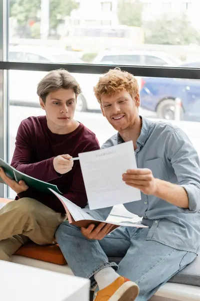 Two men engage in focused study on a windowsill. — Stock Photo
