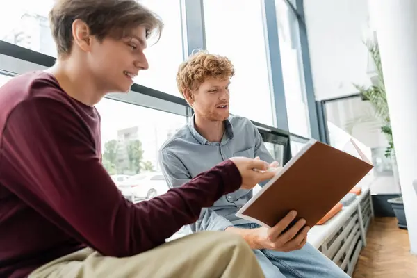 Two young men seated on a bench, engrossed in a book. — Stock Photo