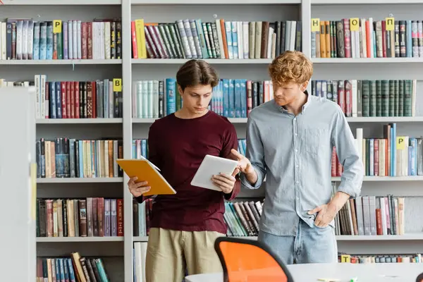 Two male students engrossed in a book at a library. — Stock Photo