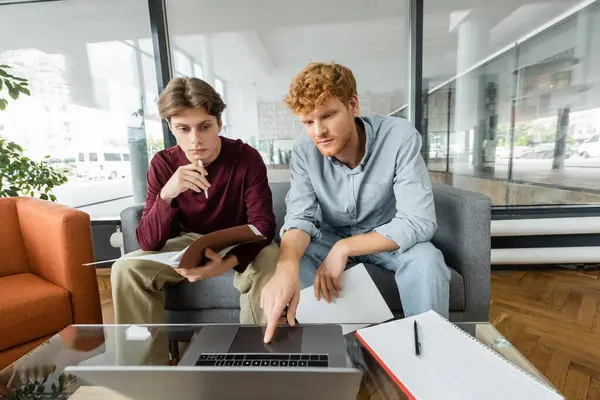 Dos personas comprometidas con un ordenador portátil mientras están sentadas en un sofá. — Stock Photo