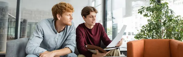 Due studenti di sesso maschile recensire le carte insieme su un divano. — Foto stock