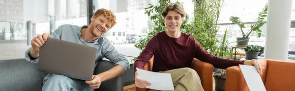 Two male students sit on a couch, focused on a laptop screen. — Stock Photo