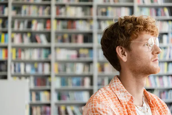 Un homme avec des lunettes debout devant une bibliothèque. — Photo de stock