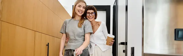 Una joven pareja lesbiana disfrutando del café en una habitación de hotel cocina. - foto de stock