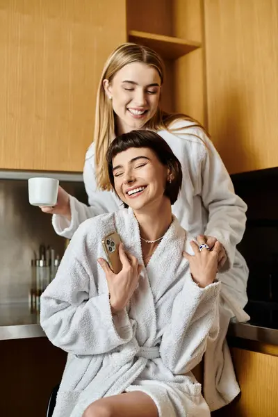 A young lesbian couple in bathrobes in a cozy kitchen setting. — Stock Photo