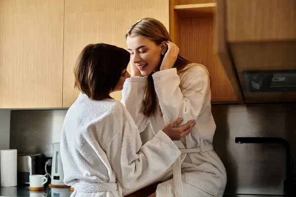 Duas jovens mulheres, um casal lésbico, se reúnem em uma cozinha elegante, mostrando amor e união. — Fotografia de Stock