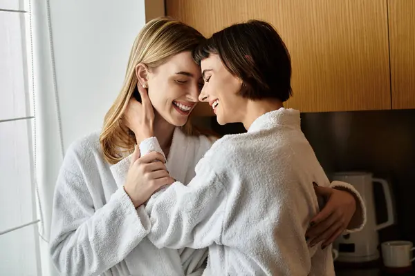Um jovem casal lésbico, em roupões de banho, preparando uma refeição juntos em uma cozinha quente e convidativa. — Fotografia de Stock