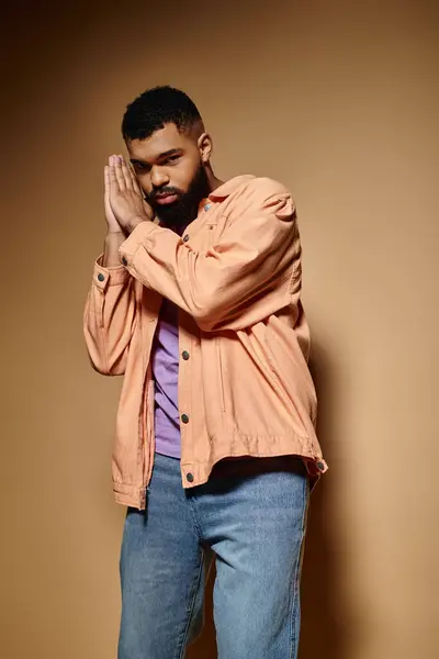 African American male in trendy clothes stands with hands together against vibrant backdrop. — Stock Photo