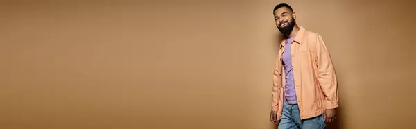 Handsome African American man in fashionable attire posing in front of a vibrant brown wall. — Stock Photo