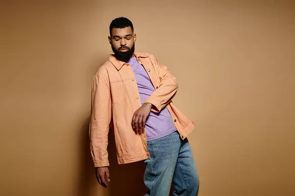 Handsome African American man posing in fashionable attire against a vibrant brown backdrop. — Stock Photo