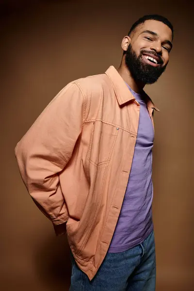 Handsome African American male in fashionable attire standing before rich brown background. — Stock Photo