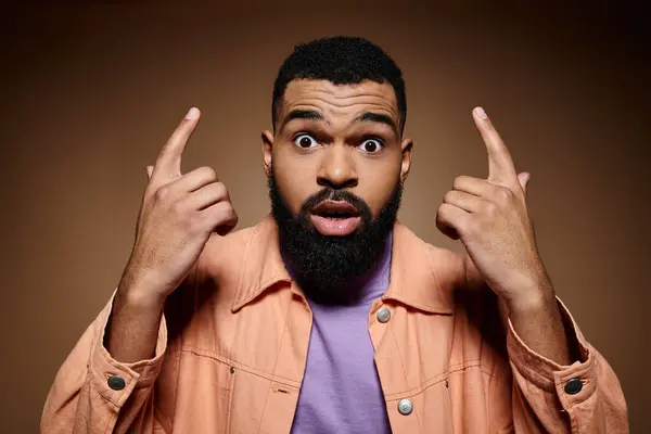 A stylish African American man wearing fashionable attire makes a funny face amid a vibrant backdrop. — Stock Photo
