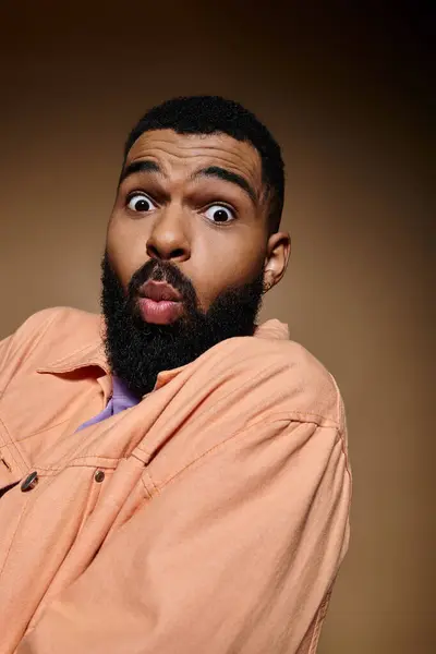 Handsome African American man looking surprised in trendy outfit against vibrant background. — Stock Photo