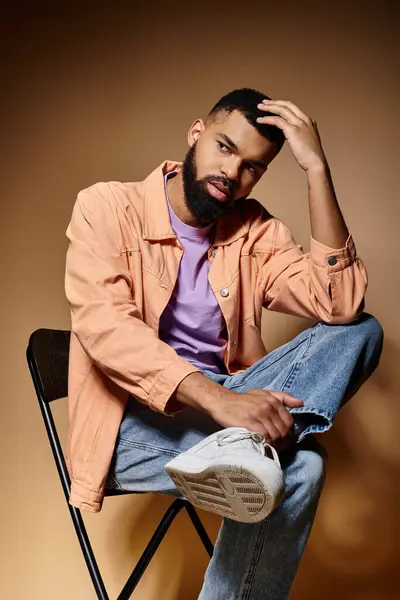 Handsome African American man sitting in a chair, hand on head, contemplating. — Stock Photo