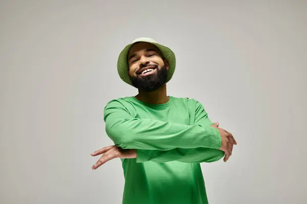 Handsome African American man in fashionable green hat and shirt posing on vibrant backdrop. — Stock Photo