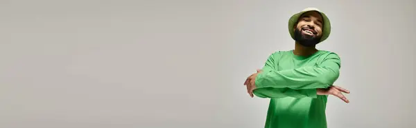 Handsome African American man in green shirt and matching hat poses against vibrant backdrop. — Stock Photo