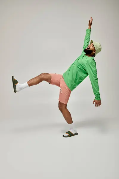 Handsome African American man in stylish green shirt performing a captivating trick. — Stock Photo