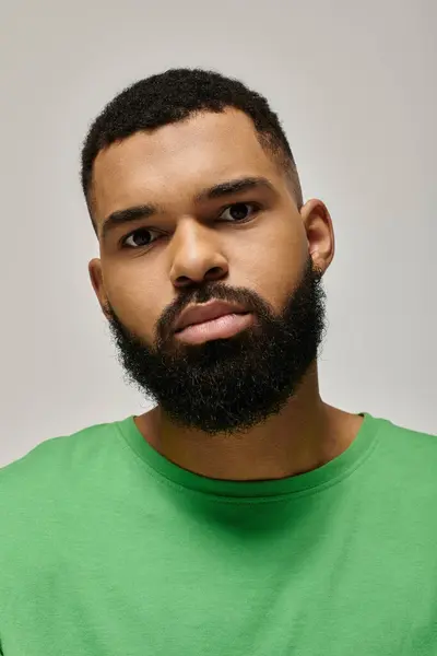 Handsome African American man with a beard confidently posing in a green shirt. — Stock Photo