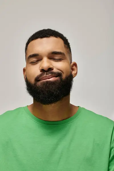 Handsome African American man with beard posing in fashionable green attire against vibrant backdrop. — Stock Photo