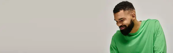 Elegante hombre afroamericano con camisa verde mirando hacia otro lado. - foto de stock