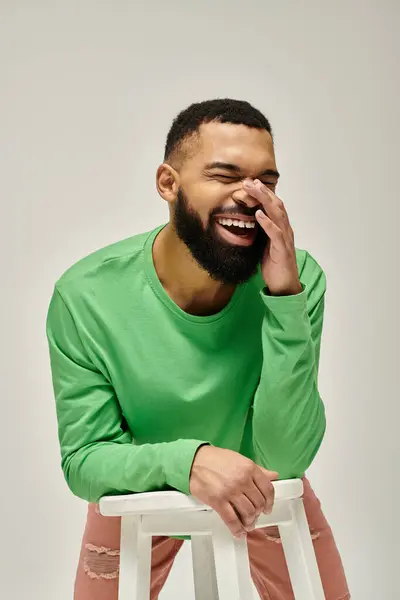 A stylish African American man with a beard, sitting on a stool. — Stock Photo
