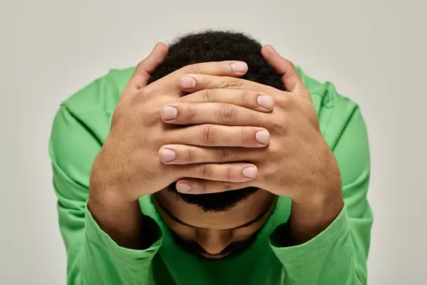 Handsome man wearing stylish attire, concealing his face with hands. — Stock Photo