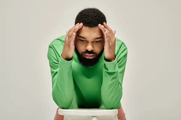 Handsome African American man in a green shirt sitting. — Stock Photo