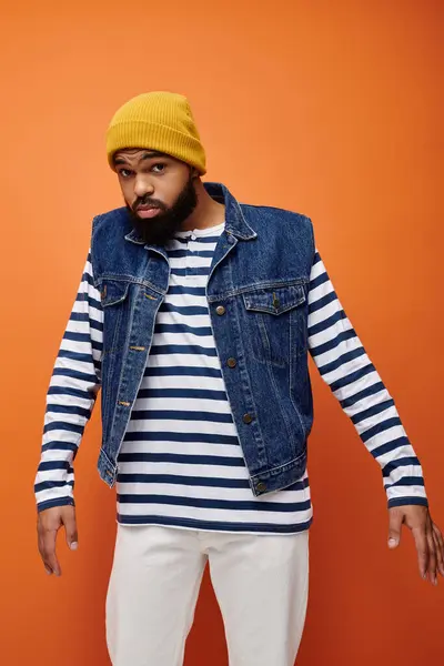 Handsome man posing in striped shirt and jean jacket against vibrant backdrop. — Stock Photo