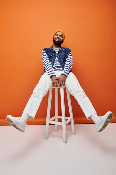 Handsome African American man in fashionable attire sitting on top of a white stool. — Stock Photo