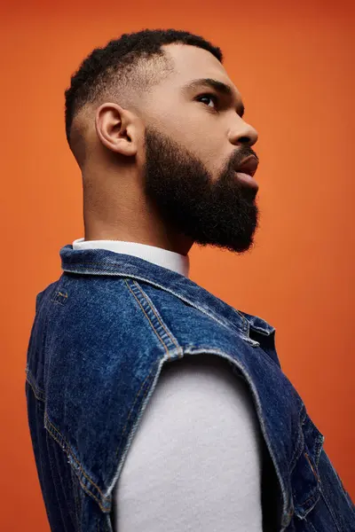 Handsome African American man posing in fashionable denim vest on vibrant backdrop. — Stock Photo