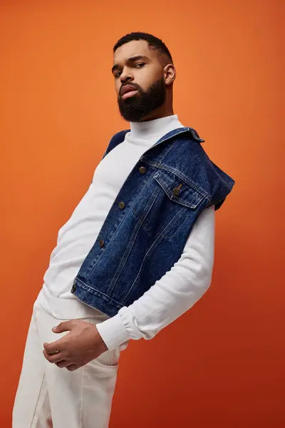 Handsome African American man poses in fashionable denim vest on vibrant backdrop. — Stock Photo