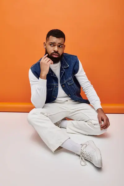 Handsome man in stylish attire, sitting with hand on chin. — Stock Photo