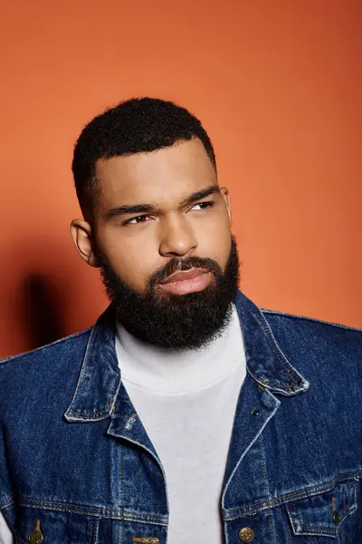 Handsome African American man poses in fashionable denim jacket against vibrant backdrop. — Stock Photo