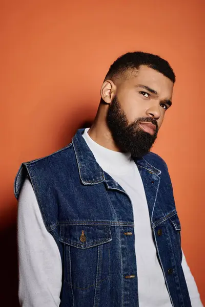 Handsome African American man posing in fashionable denim vest on vibrant backdrop. — Stock Photo