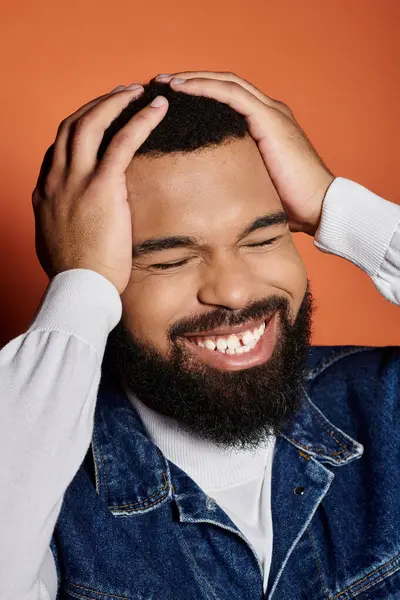 Stylish man with beard smiling and pondering, hands on head. — Stock Photo
