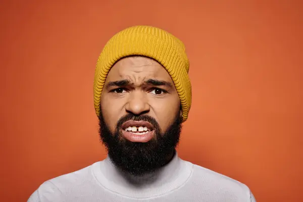 Stylish African American man with beard, wearing a yellow hat against a vibrant backdrop. — Stock Photo