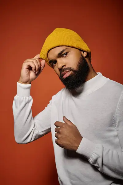 Handsome African American man with a beard wearing a yellow hat in a stylish pose against a colorful backdrop. — Stock Photo