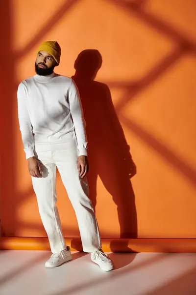 Handsome man poses in front of a vibrant orange wall. — Stock Photo