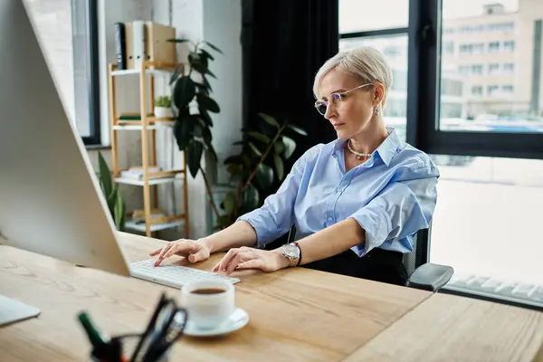 A middle-aged businesswoman with short hair focused on her laptop while working in an office during menopause. — Stock Photo